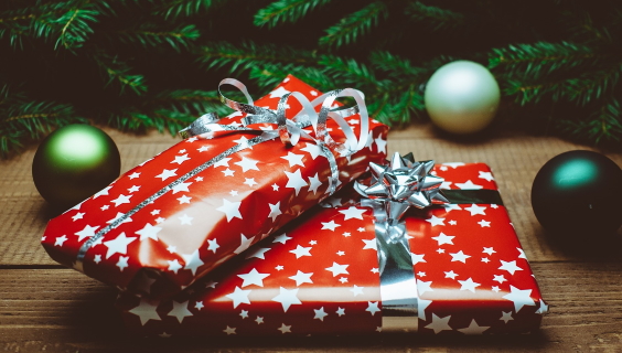 Under juletræet ligger to gaver pakket i rødt papir med hvide stjerner